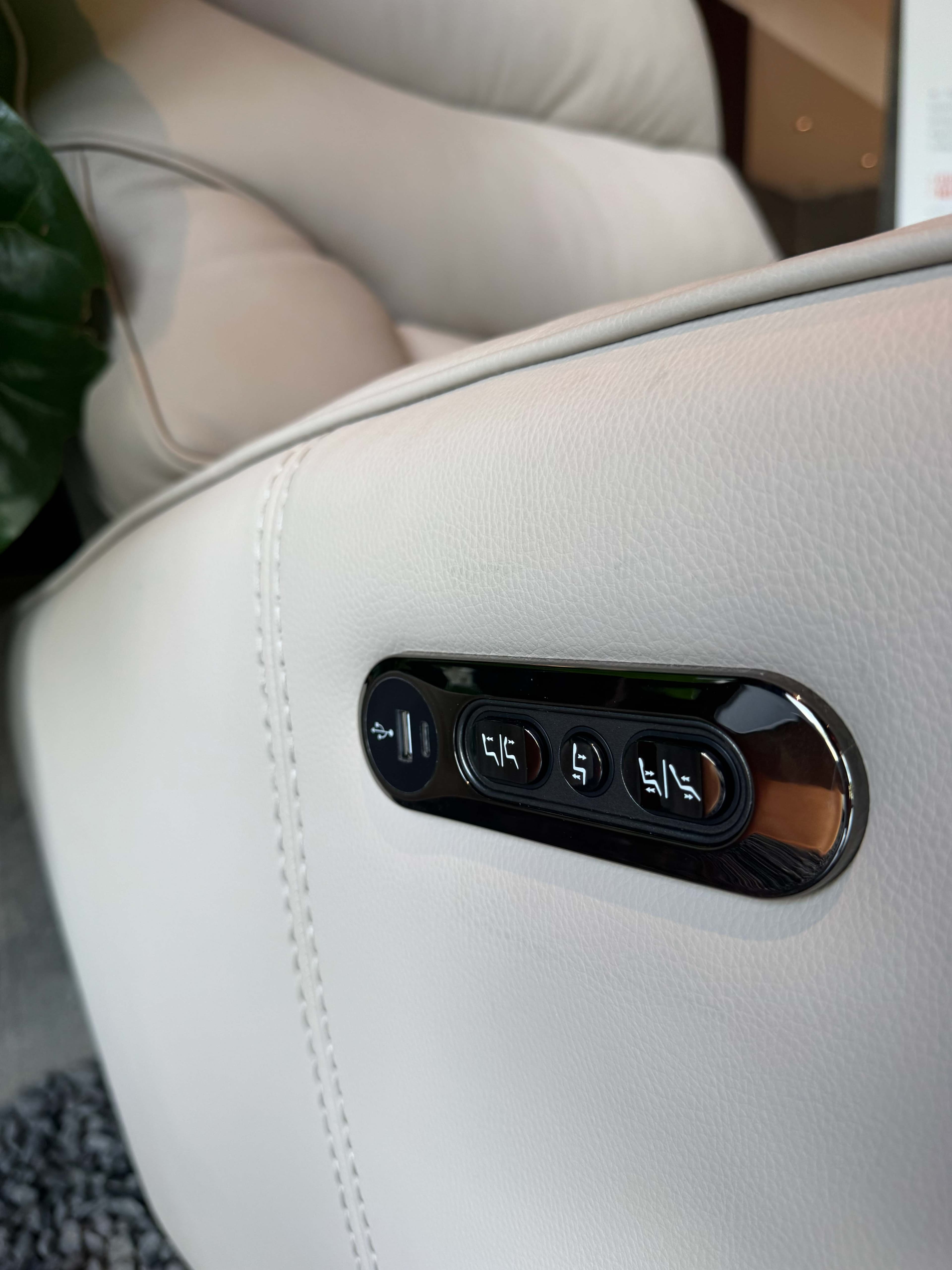 Power recline buttons on the side of a leather motion chair